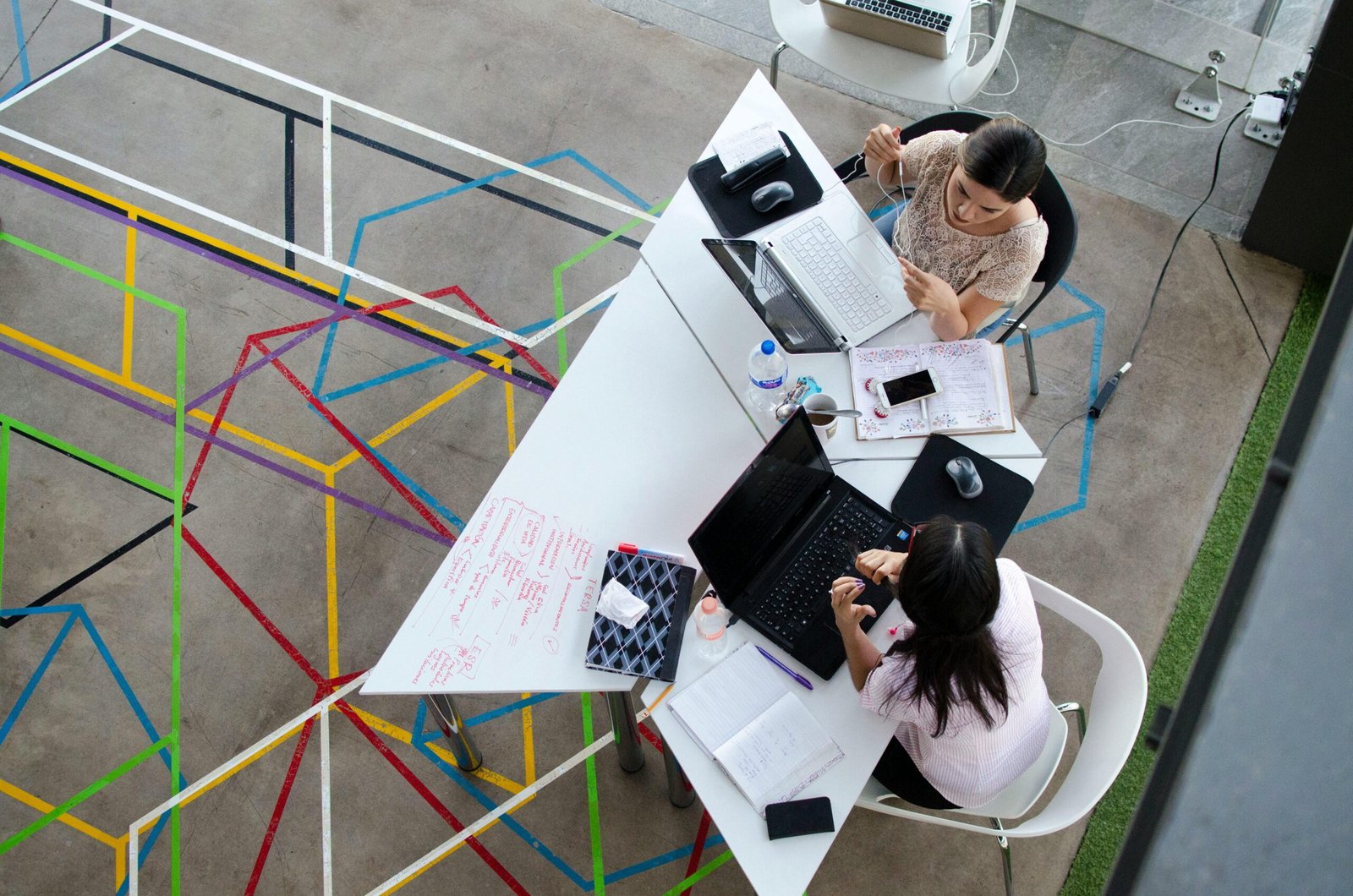 Overhead view of women working together in a modern office setting with colorful geometric floor design.